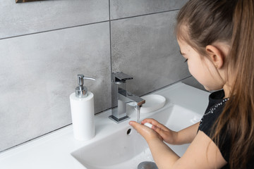 Dziewczynka myje ręce w łazience. Mycie i dezynfekcja rąk mydłem i płynem antybakteryjnym. - obrazy, fototapety, plakaty