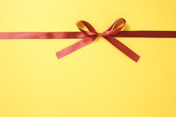 黄色い背景に蝶結している赤いリボン 01