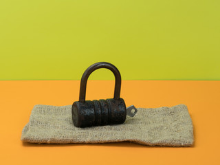 Retro lock and key on burlap on orange and green background.