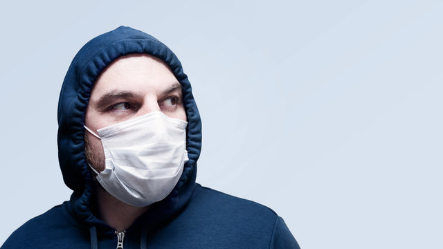 Corona virus. Young man in a face mask on a uniform background, isolate. Protection against infection, virus, dust