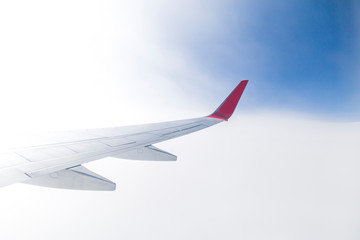 Empty airplane wing view via passenger window with blue sky, clean and modern look