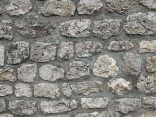 wall composed of large old stones sealed in grey concrete