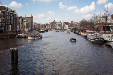 Amsterdam city view with canals and boats in autumn with clouds and blue sky