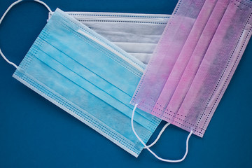 Multi-colored disposable medical masks on a blue background.