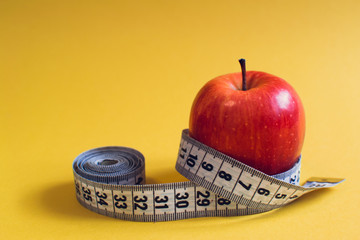 Healthy lifestyle concept. Red apple with measuring tape. Dieting concept.