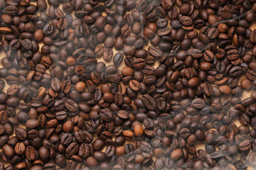 handful of hot coffee beans on wooden background with steam