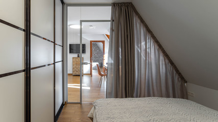 Modern contemporary interior of bedroom. Sliding wardrobe. Cozy bed. Zoning with curtain.