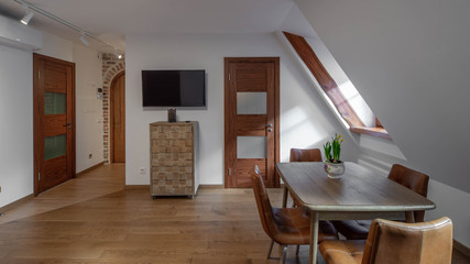 Modern contemporary interior of living room with furniture and tv. Sloping ceiling. Private house.