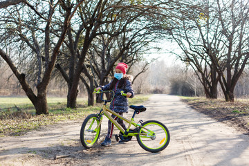 Fototapeta premium 7 years old happy Little girl child ride bicycle in the park at home and wearing protection mask for protect pm2.5 and Coronavirus Covid-19 Pandemic virus symptoms.Sport exercise for health.