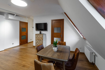 Modern contemporary interior of living room with furniture and tv. Sloping ceiling. Private house.
