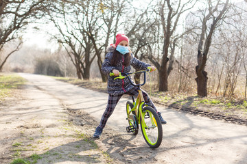 7 years old happy Little girl child ride bicycle in the park at home and wearing protection mask for protect pm2.5 and Coronavirus Covid-19 Pandemic virus symptoms.Sport exercise for health.