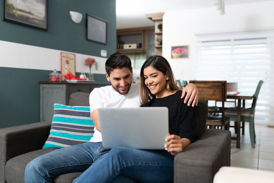Smiling Couple Using Laptop At Home