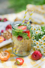 Mason jar glass of lemonade with lemons, strawberry and mint leaves