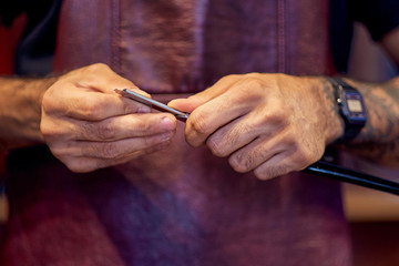 Cropped image of barber in stylish classic wear holding a straight razor