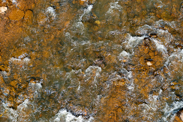 A background texture of a river flowing over brown rocks