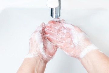 Washing hands with soap under the faucet with water