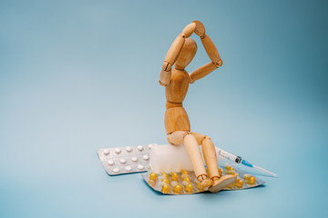 The wooden figure sits next to the pills.
