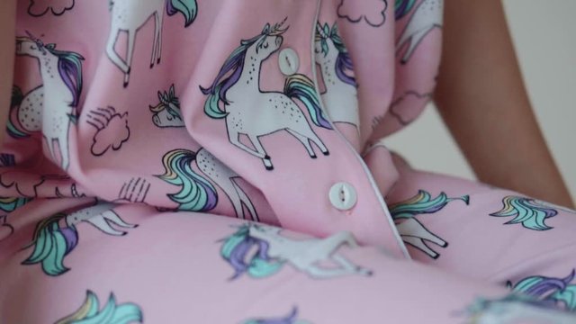 Button on pink pajamas close-up. Background slow motion video with quality fabric.