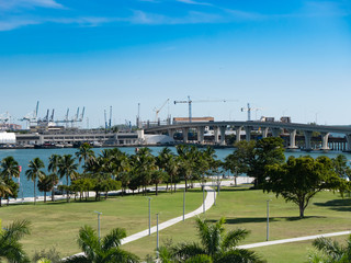 Fototapeta na wymiar Port of Miami water front park, bridge overpass, and cranes for loading ships.