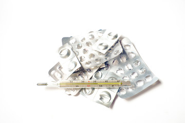 On a white background a lot of empty packages from tablets and medical mercury thermometer