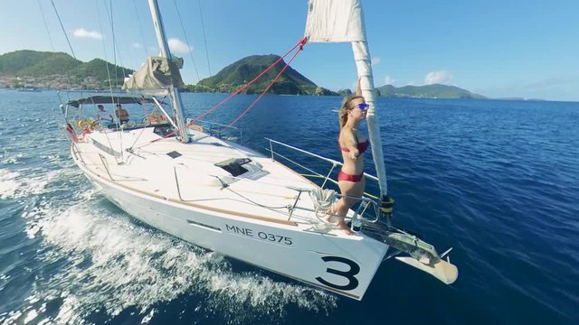 Half-round view of a sailing yacht with a woman relaxing on it