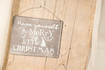 A Merry Little Christmas board decoration hanged on a wooden wall