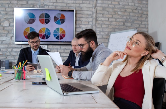 Team of young business people and designers working in a modern retro style office. Beautiful young business woman daydreaming in front of her laptop. Startup concept.