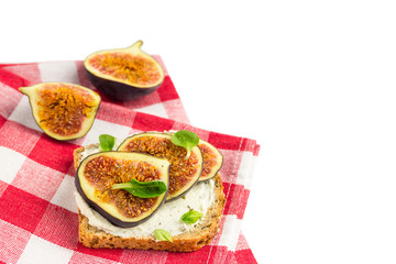 Sandwich with cream cheese, figs, honey and leaves salad served on the cloth on white background. Healthy food concept. Top view