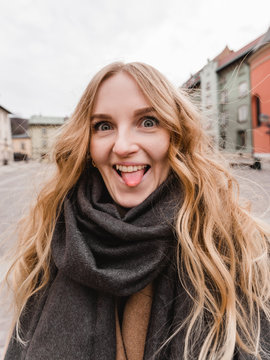 Beautiful young tourist woman making selfie and grimacing. Pretty girl having fun showing tongue