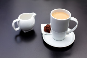 Obraz na płótnie Canvas A cup of coffee with milk jug on metallic background.