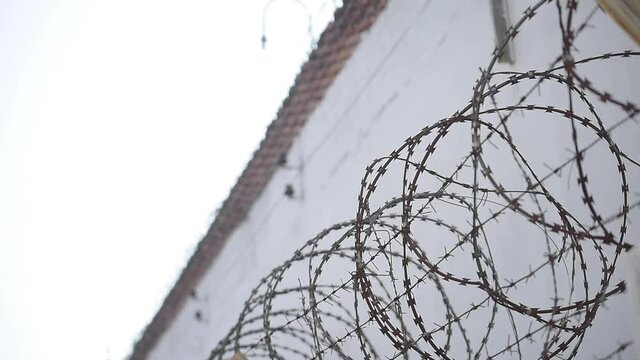 wall of the prison building high fence with barbed wire