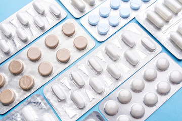 Pills in blister packs on blue background. Medicine concept.