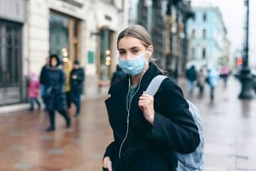 Prevention of coronavirus outbreak in 2020. Portrait of young european woman wearing a mask in the city street. Prevent pollution and disease concept.
