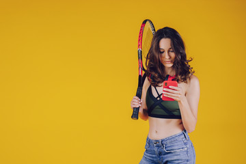 A young and friendly lady, well-disposed, with a smile and sporty dress, makes selfies and holds in your hand a tennis racket.