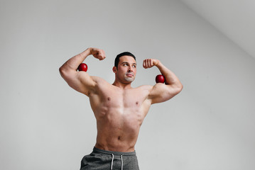 Sporty sexy guy posing on a white background with bright fruits. Diet. Healthy diet