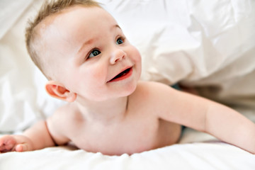 cute baby boy lying on a white bed