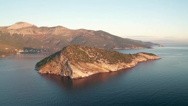 Drone flight around the mountain slopes and rocky coastline of Thasos island and the little island Nisida Kinira, Greece