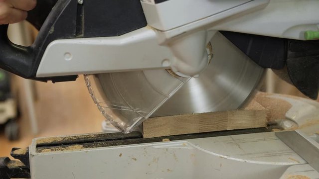 Close-up of a woodworker cutting a plank with a circular saw