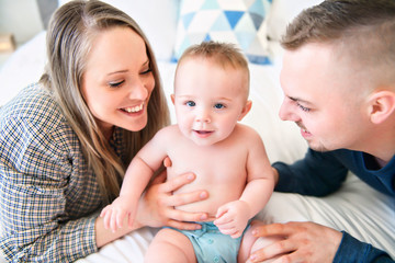 happy family and their baby boy on the bed at home