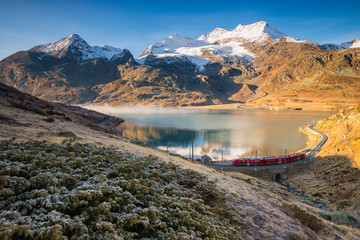 Swiss train near the white lake in background the alps peaks, Bernina Pass, Switzerland