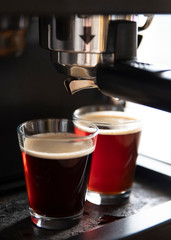 Close-up of a coffee machine pouring coffee into cups
