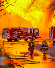 Two brave firefighters assist the crews to extinguish a gas line explosion in the roadway