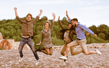 Group of smiling young multiracial friends trying to jump up