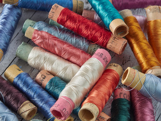 Blue and colored silk threads on paper sleeves.Vintage threads lie on a blue background