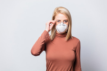Beautiful blonde woman in glasses and face mask on white background