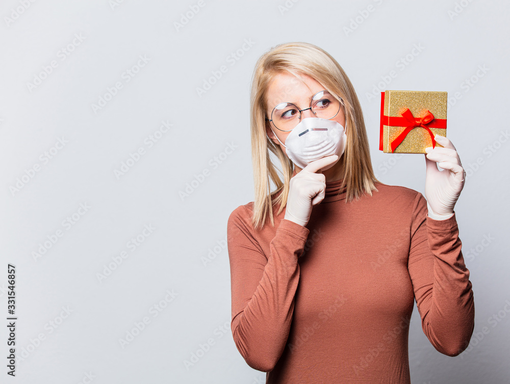 Wall mural style blonde woman in face mask with gift box on white background