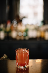 Cocktail in a rocks glass decorated with a dried slice of peach. Dark background. Smooth image with shallow depth of field.