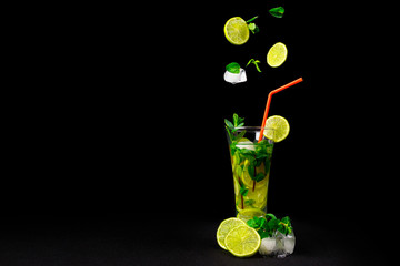 Glass with lemonade or mojito cocktail in freeze motion on a black background.
