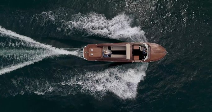 old mahogany motor boat is sailing along the beautiful Lake in Italy Aerial shot