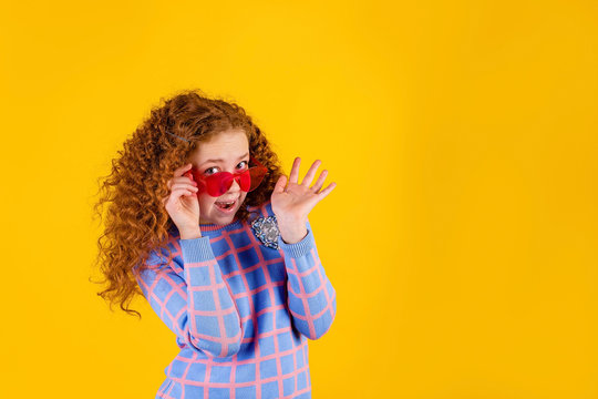 red haired , emotional girl with red glasses on a yellow background